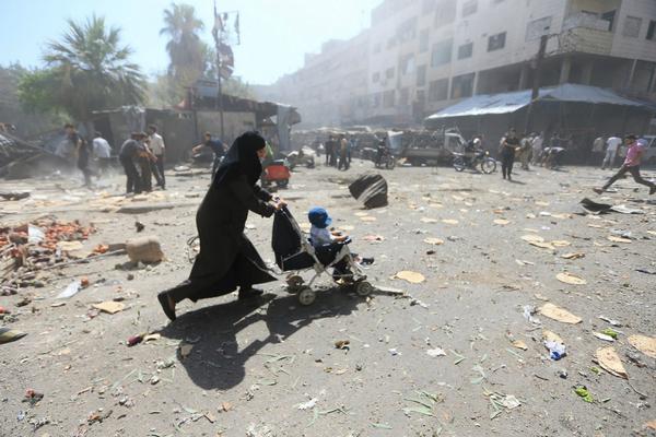 ETANASYRIA's tweet photo. Woman rushes away after an Assad regime airstrikes on marketplace in #Douma, #Damascus, #Syria  Wed. Aug. 12 #Reuters http://t.co/keh8xMP6ZT