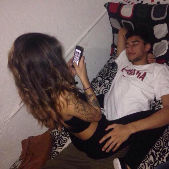 {Hums softly, scrolling through her phone as she sits on his lap}