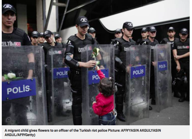 7piliers's tweet photo. Refugee child hands flower to Turkish riot police who are blocking the border

http://t.co/hckZ7AhAx7 via @MetroUK http://t.co/CXwvf9OVUd