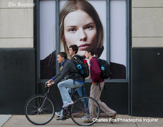 PhillyLens's tweet photo. Pedestrians pass a window ad in University City in Philly yesterday afternoon. http://t.co/sc2L9qlGwZ