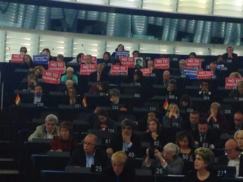 RogerHelmerMEP's tweet photo. At the Merkel &amp; Hollande event in the EP: the hard left's banners read "No to austerity" and "Refugees Welcome". http://t.co/qpGORfz2ng