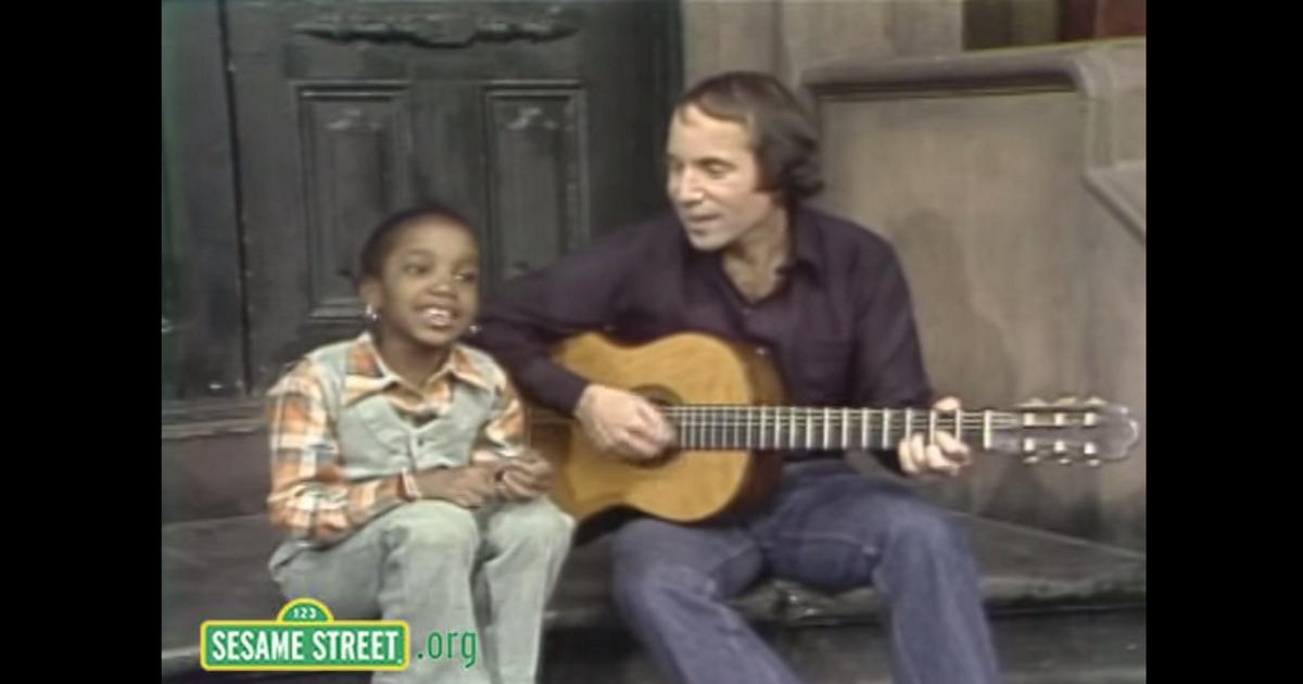 A little girl steals spotlight from birthday boy Paul Simon during 1977 visit to Sesame St.  