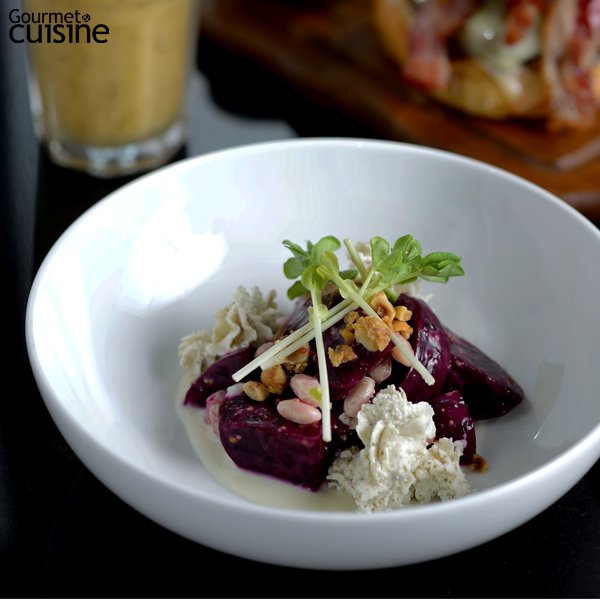 เมนูห้ามพลาดของร้าน Jones The Grocer บีตรูทต้มหั่นสีเหลี่ยมวางบนซอสถั่วขาวบดและโรยหน้าด้วยถั่วขาวและเฮเซลนัตครัมเบิล