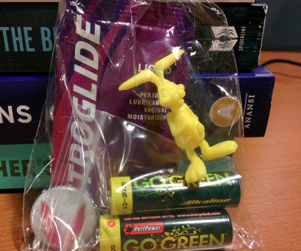 Cellophane bag containing vaginal lubricant, a yellow plastic rabbit, two AA batteries, and a pin