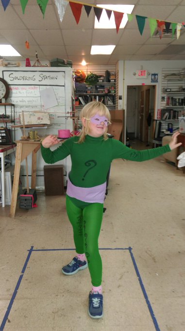 adorable child in Riddler costume in front of a soldering station
