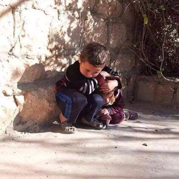 Kız kardeşini hava saldırısından korumaya çalışan bir Suriyeli çocuk...