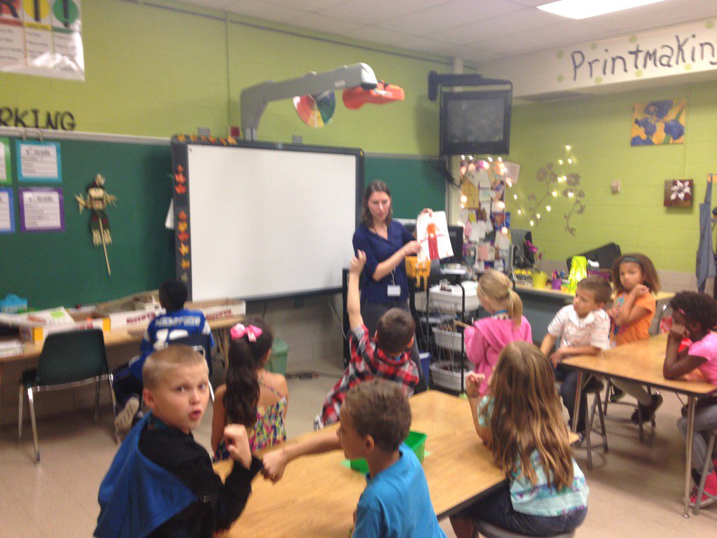 A student is helping the teacher demonstrate the next step in creating a scarecrow at Sandy Plains.