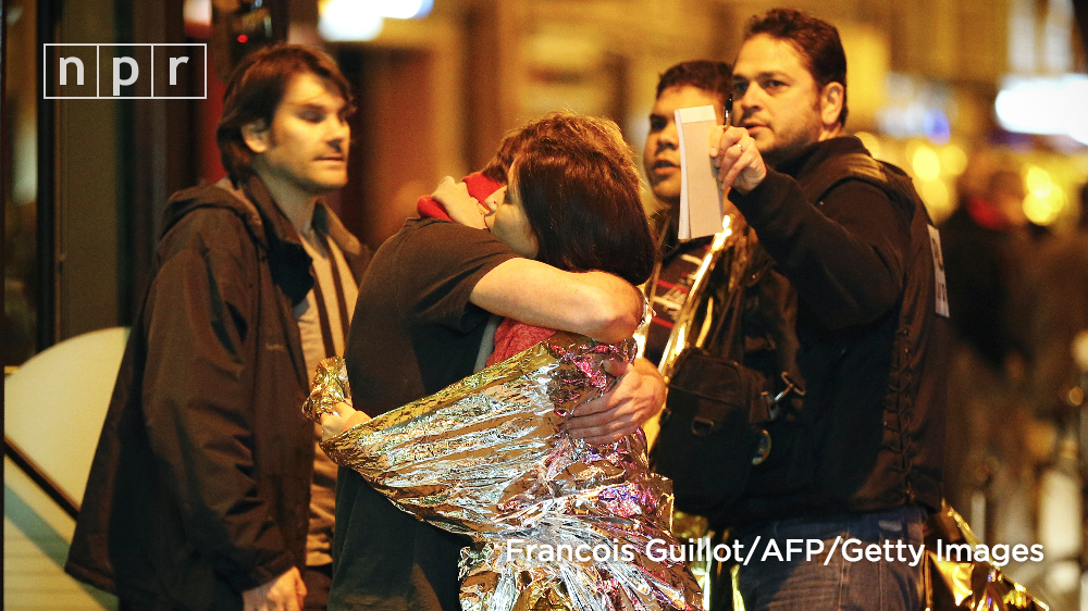 NPR's tweet photo. IMAGE: People hug before being evacuated near the Bataclan concert hall in Paris. STORY: https://t.co/dcb3tJck7R https://t.co/qk3Gzn21FJ
