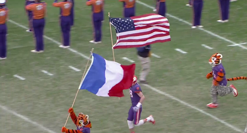 ESPNCFB's tweet photo. Clemson takes the field holding the French and American flags. https://t.co/SOT3XAjTd2