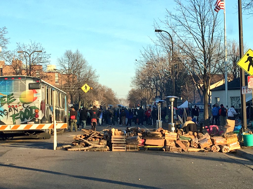 Piles of firewood block both ends of the street in front of the 4th District Police Station in Minneapolis