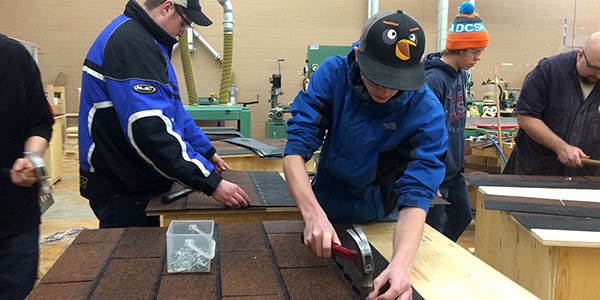 College Heights construction students putting the shingles on dog houses for the Northern Dogs Project <a href="/CHSSHuskies/">College Heights</a>