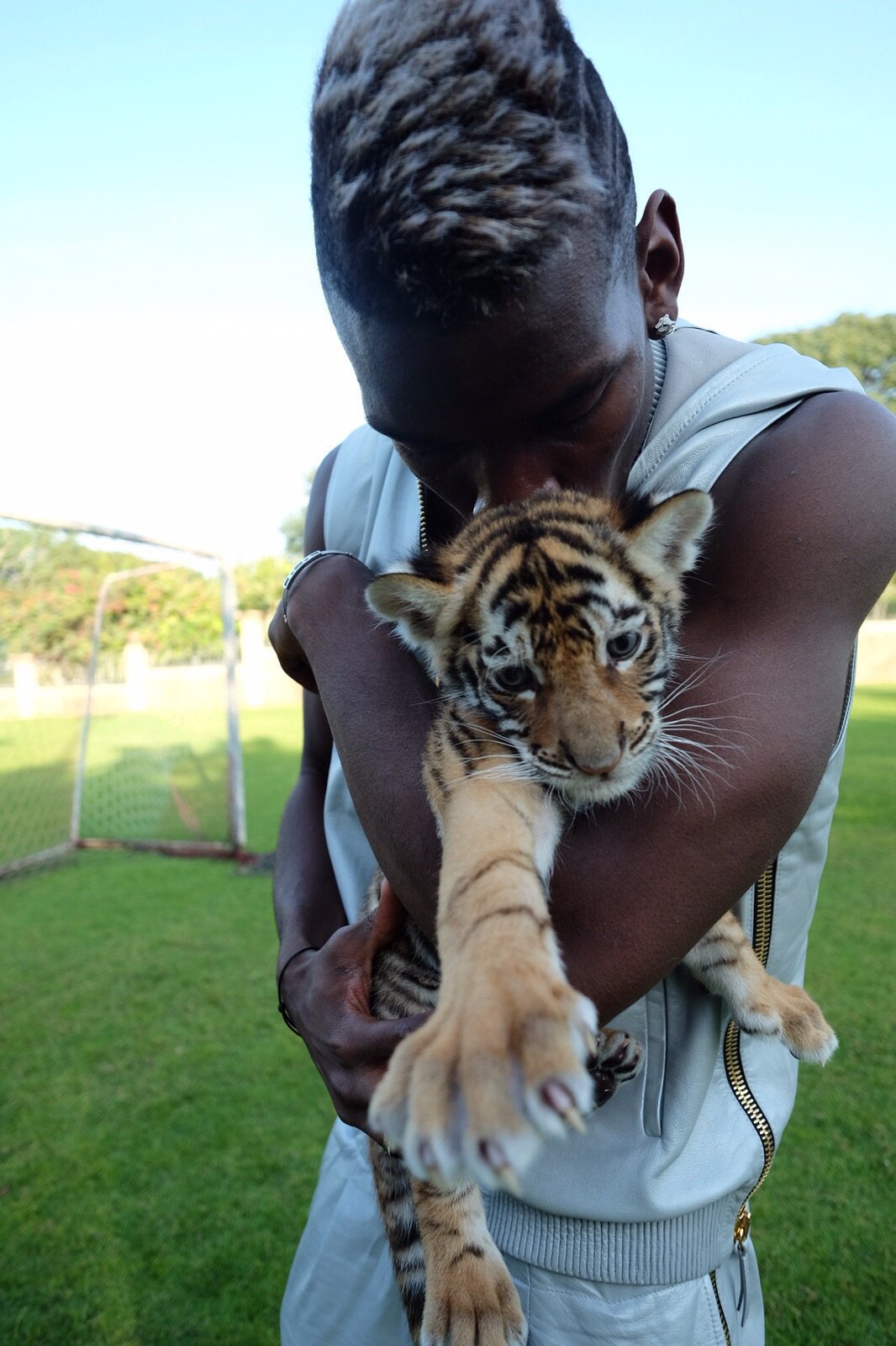 Paul Pogba wearing a tiger T-shirt, leather jacket and specs.