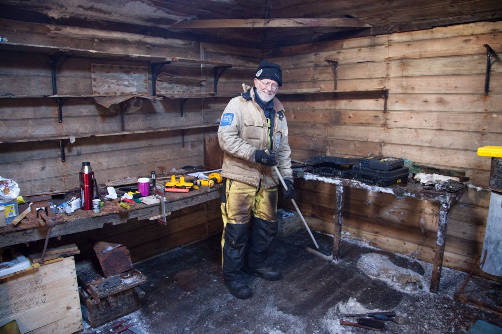 mawsonshuts's tweet photo. Conservator Peter Maxwell sweeps the floor in the workshop of Mawson's 
Hut after removing the snow and ice . #maws… https://t.co/hcWcFiQsvK