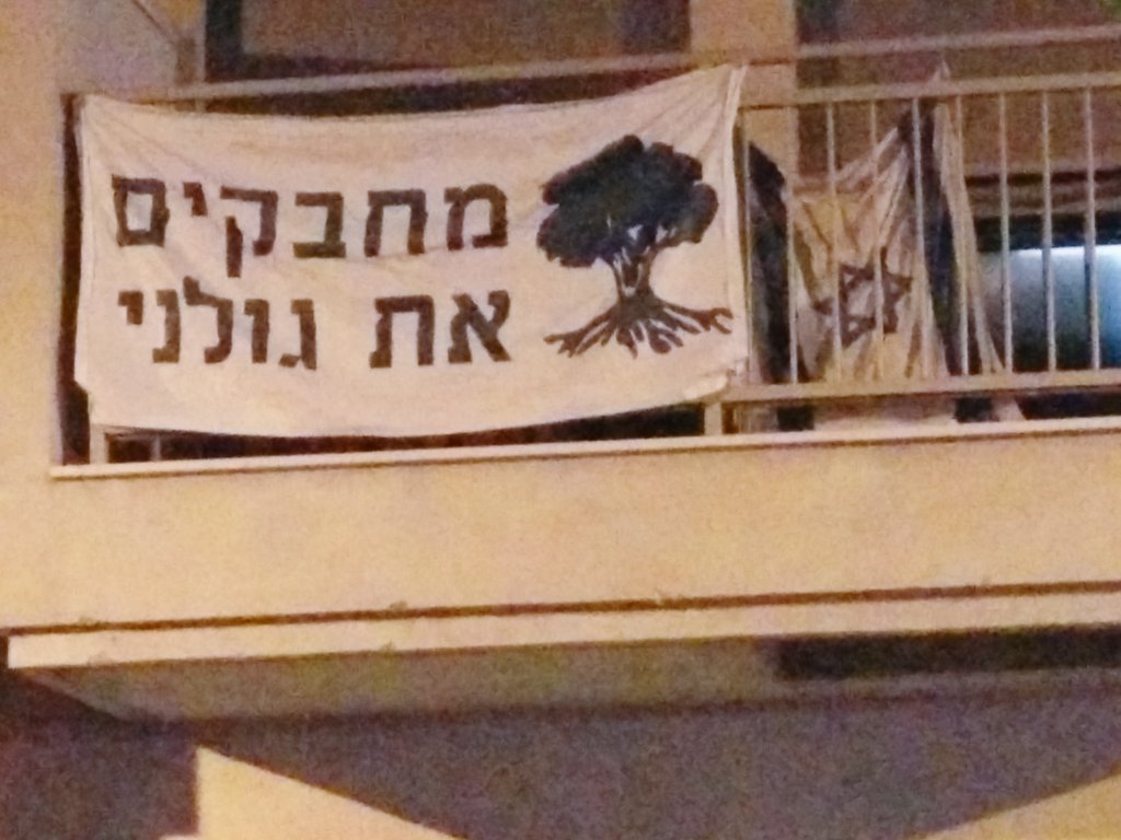 RenenRaz's tweet photo. From the opening of the massacre in #gaza of last year. On the banner in Hebrew in tel Aviv. Hugging Golani bridge. https://t.co/Kxlazrefmz