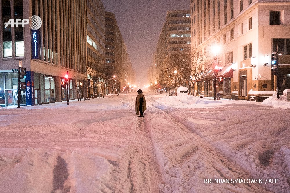 A homeless woman stands in the street after a snowstorm in Washington, DC. By Brendan Smialowski #AFP