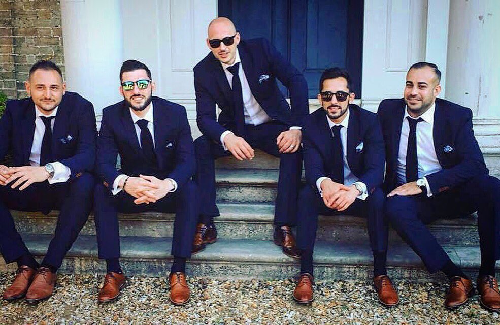 A navy slim fit 2 piece medium weight suit. White cotton shirts with double cuffs, navy wool knitted ties, Silk Paisley pocket squares...