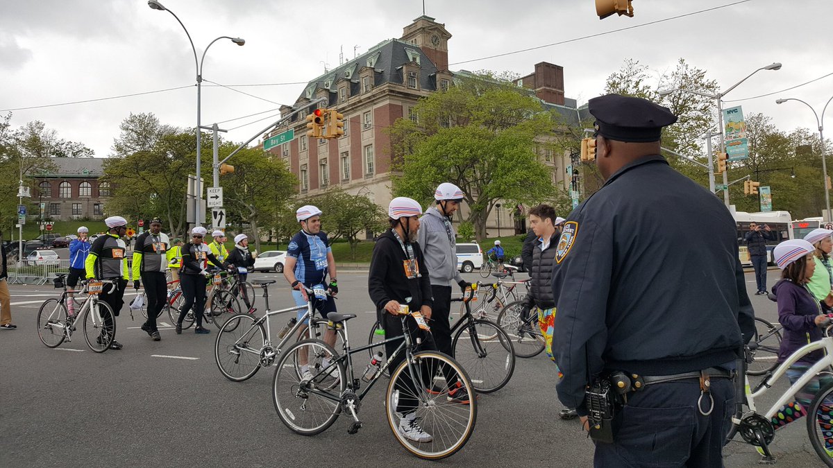 cyclists walking their bikes to the Staten island ferry terminal. there is a cop in the foreground