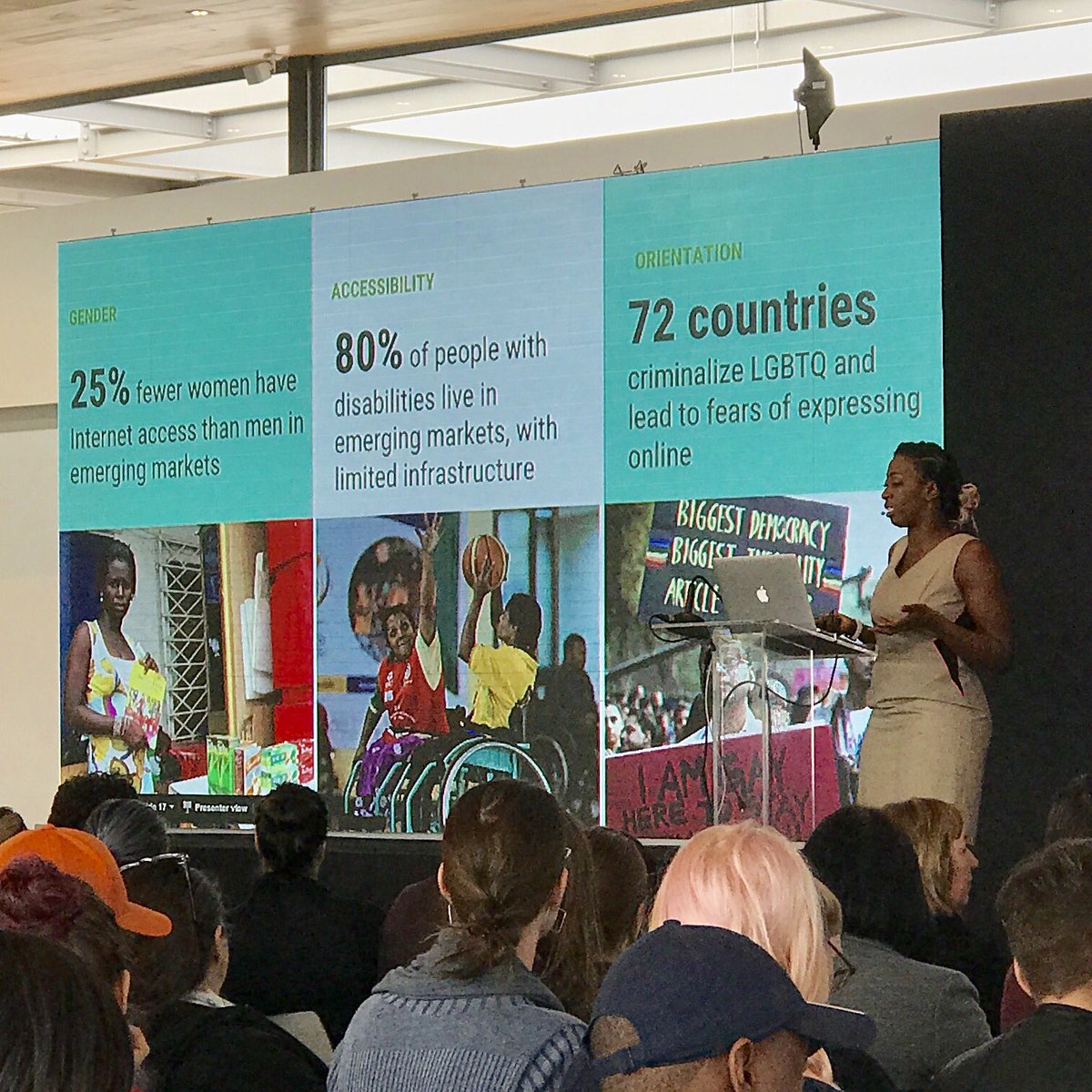 Nancy Douyon on stage presenting facts on screen about gender, disability, and LGBTQ communities.