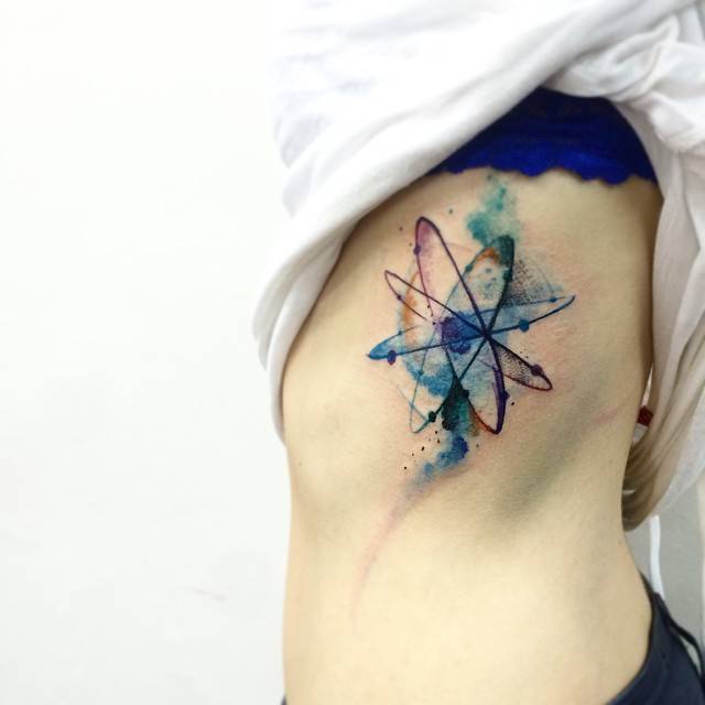 Fine line atom tattoo located on the