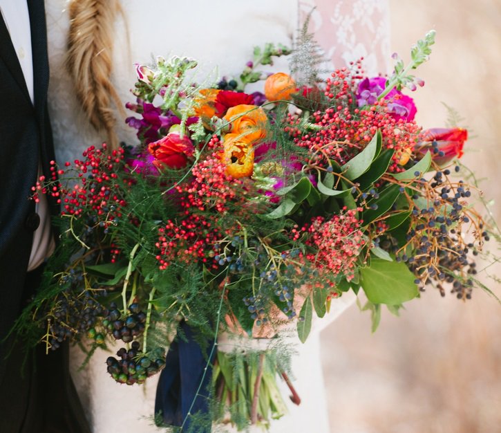 We <3 this bride's bouquet filled with red and dark blue berries, peonies and ranunculus: knot.ly/6011Bj0WZ