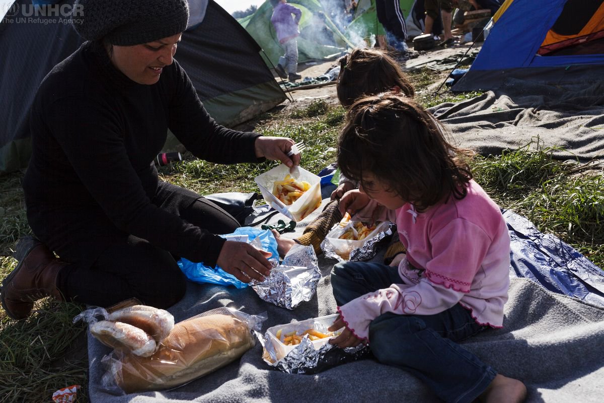 UNHCRUK's tweet photo. Syrian refugee Nisrine feeds her daughters aged 3 &amp; 4 outside a small tent the family sleeps in at Idomeni, Greece https://t.co/WXFM1JhWKi