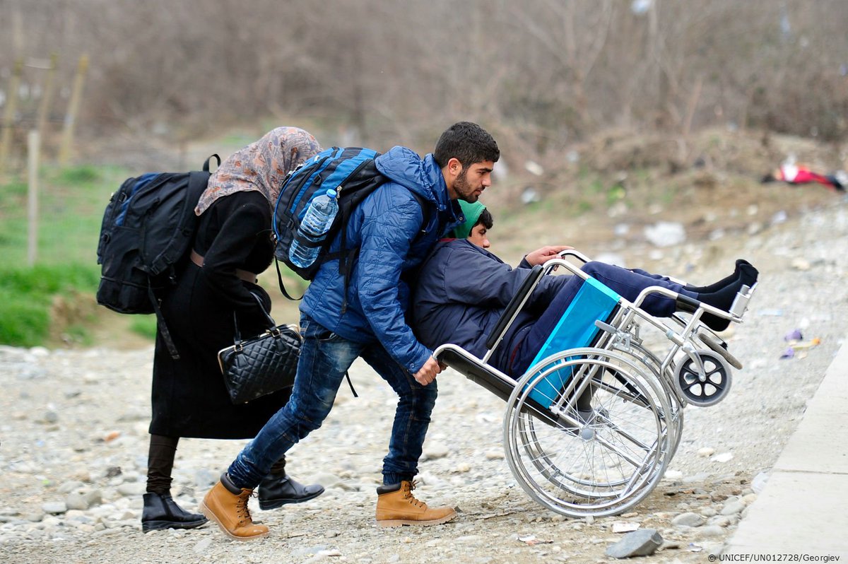 UNICEF's tweet image. A man helps a boy in a wheelchair to the train outside Vinojug transit center, near Gevgelija, #fyrMacedonia