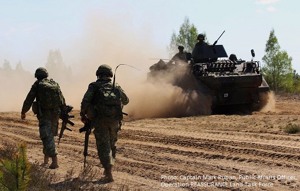 CanadaLithuania's tweet photo. #Lithuanian armoured personnel carrier passes by Canadian soldiers of #OpREASSURANCE during #ExHUNTER in #Lithuania https://t.co/pLuYrPp9dI