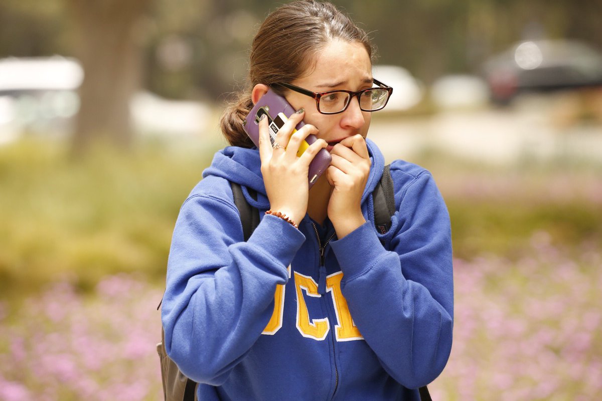 Gabriela Romero calls her mom as students are released on UCLA campus after two people were shot and killed Wednesday. (Al Seib / Los Angeles Times)