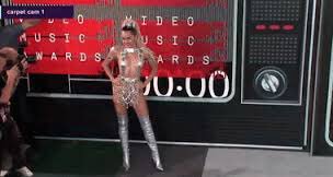 *She steps out onto the carpet and poses so the photographers can snap pictures and she sticks her tongue out*