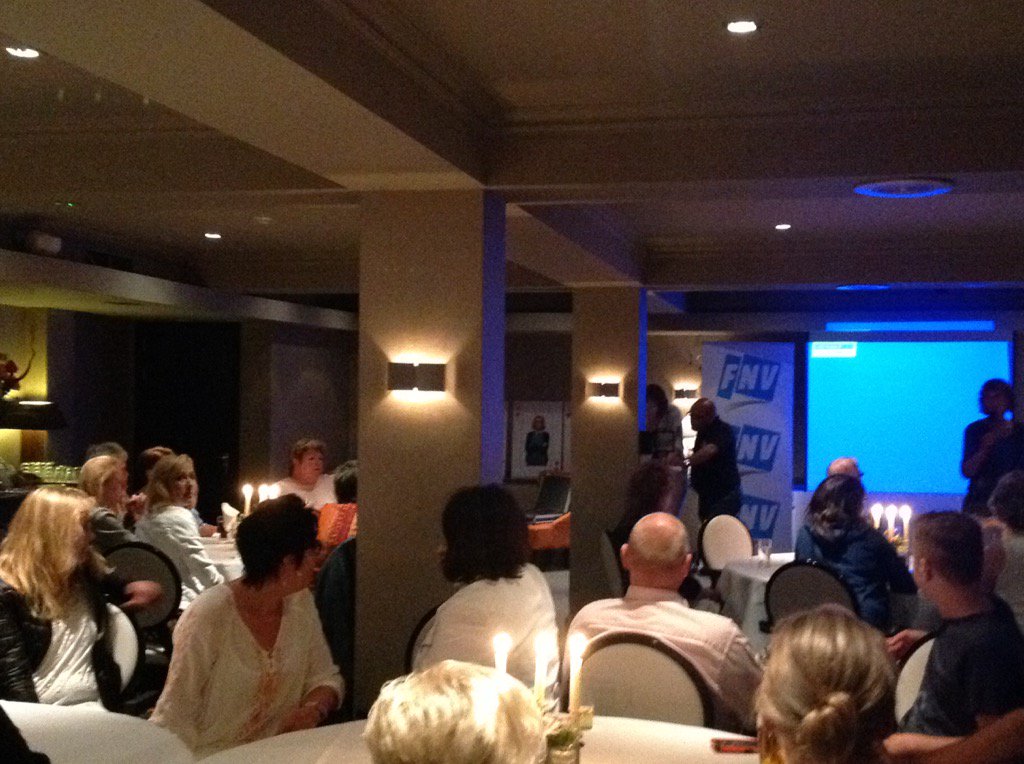 Volle zaal met vrouwen en mannen van Verian die feest vieren. Werk, uren, zelfde arbeidsvoorden strijden vanaf 2014