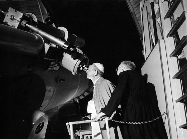 Through the Vatican observatory's telescope, the Pope is disconcerted to see the face of God wink at him knowingly.