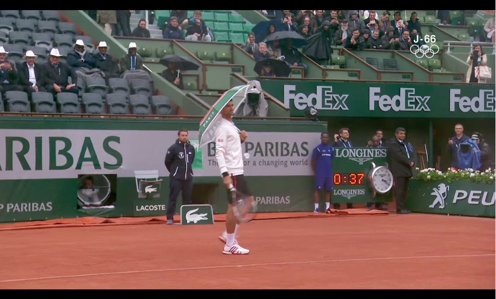 L'une des images du jour. Djokovic se promenant sur le Central, après avoir emprunté ce parapluie à une dame. #RG16