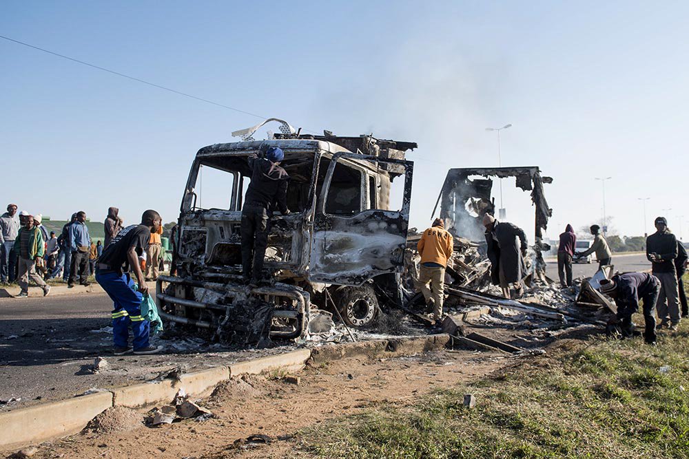 A burned out truck in Hammanskraal outside Pretoria on the R101 being looted. <a href="/Netwerk24Berig/">Netwerk24 Berig</a> #TshwaneUnrest
