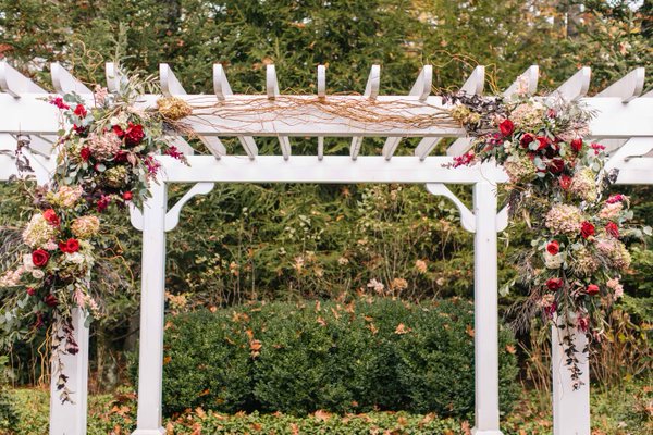 WeddingYear's tweet photo. A white arch decorated with wine-colored blooms on vines https://t.co/Fxc9ehcN4E