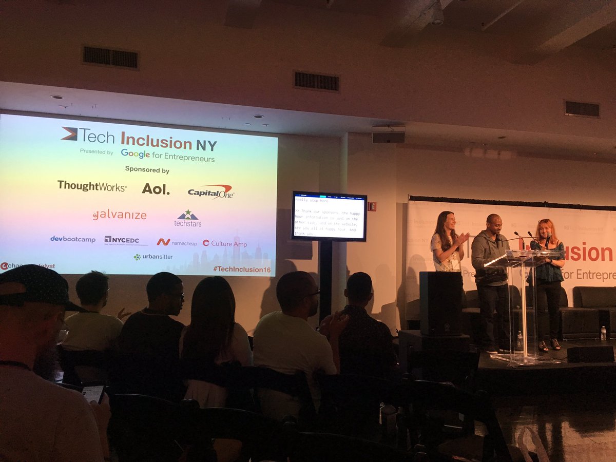 Screen on left showing logos of tech inclusion ny sponsors. Monitor in middle showing live captioning. Three people standing on stage: Laura Frey, Wayne Sutton, Melinda Briana Epler.