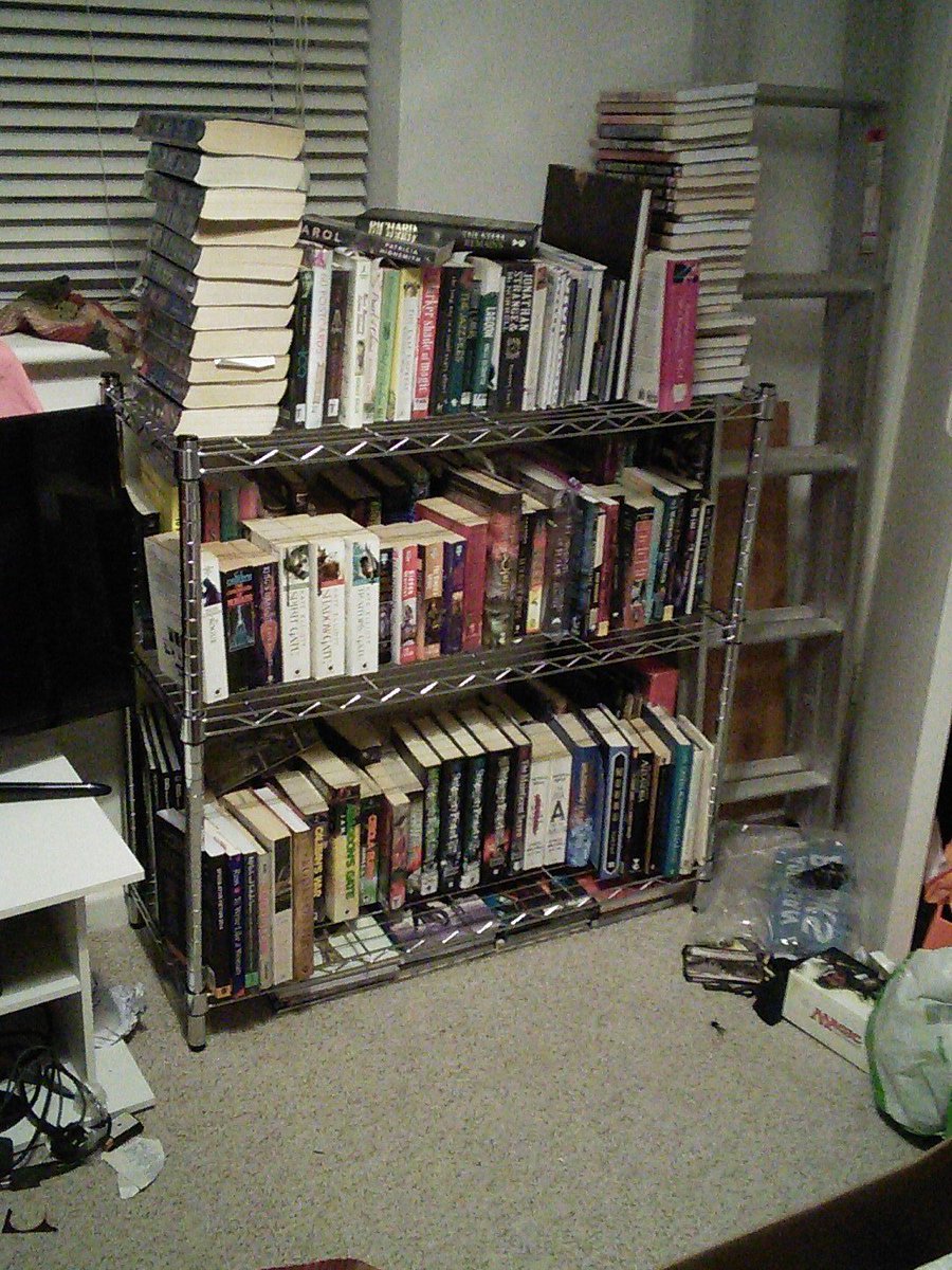 A bookcase with books double and triple stacked on it.
