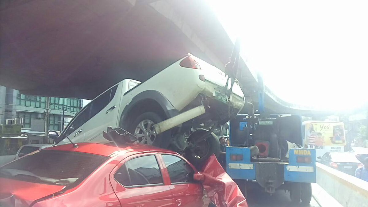 ABSCBNNews's tweet photo. LOOK: @MMDA crane now attempting to remove pickup atop pileup https://t.co/ylFiJOyXcT | via @anjo_bagaoisan