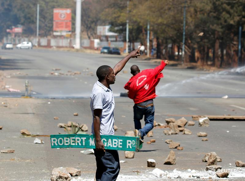 ReutersAfrica's tweet photo. A man carries a street sign as opposition party supporters clash with police in Harare, Zimbabwe, August 26,2016. https://t.co/sANYztX764