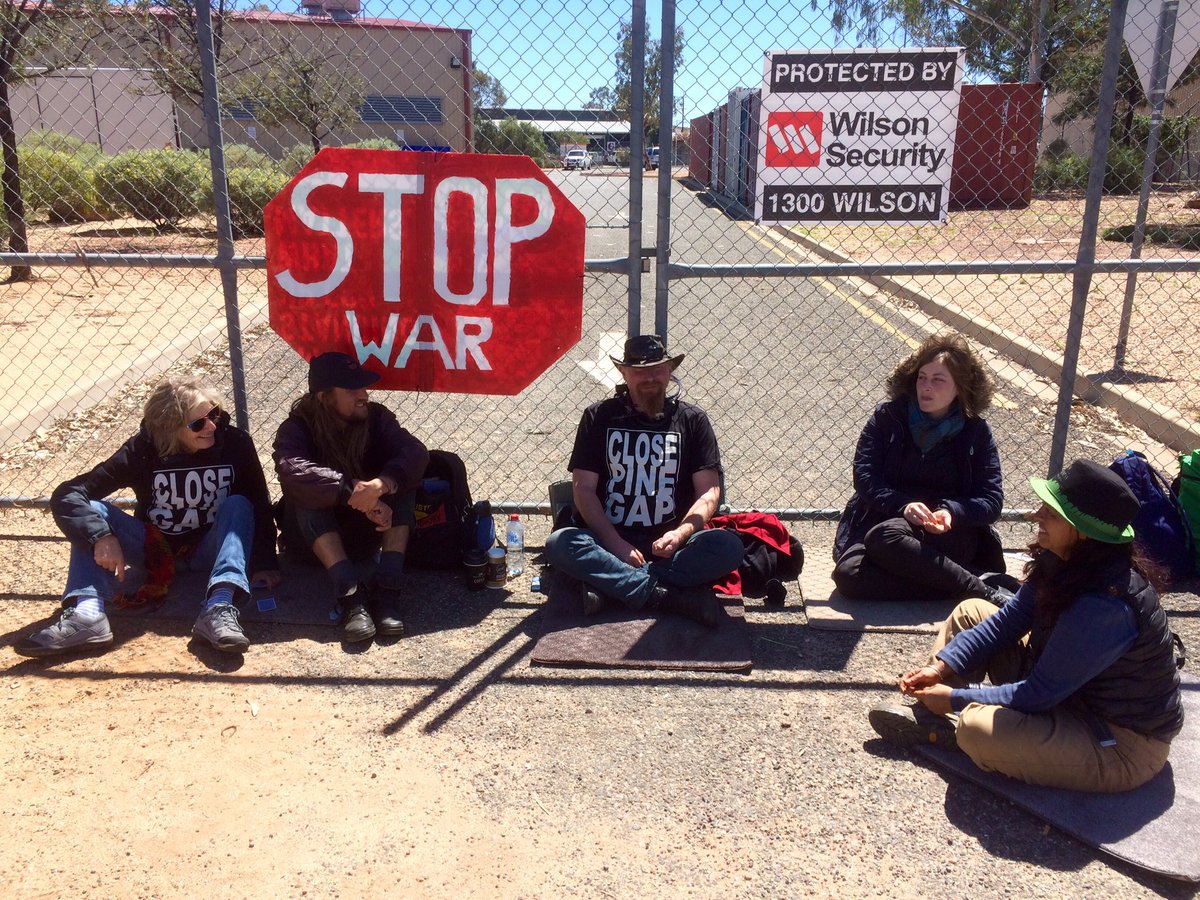 ClosePineGap's tweet photo. Lockon blockade of Raytheon in Alice Springs by antiwar activists enters hour 7. https://t.co/dnp3OuGBp9  #ClosePineGap #KillerDrones #NoWar https://t.co/2mAqeNKLXi
