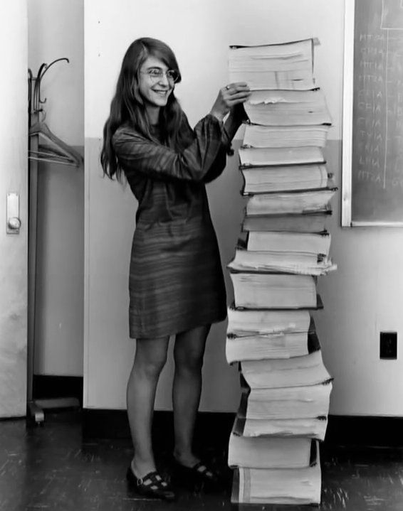 amyhoy's tweet image. margaret hamilton, nasa programmer, standing next to a printout of the javascript she wrote to dynamically load hamburger menus