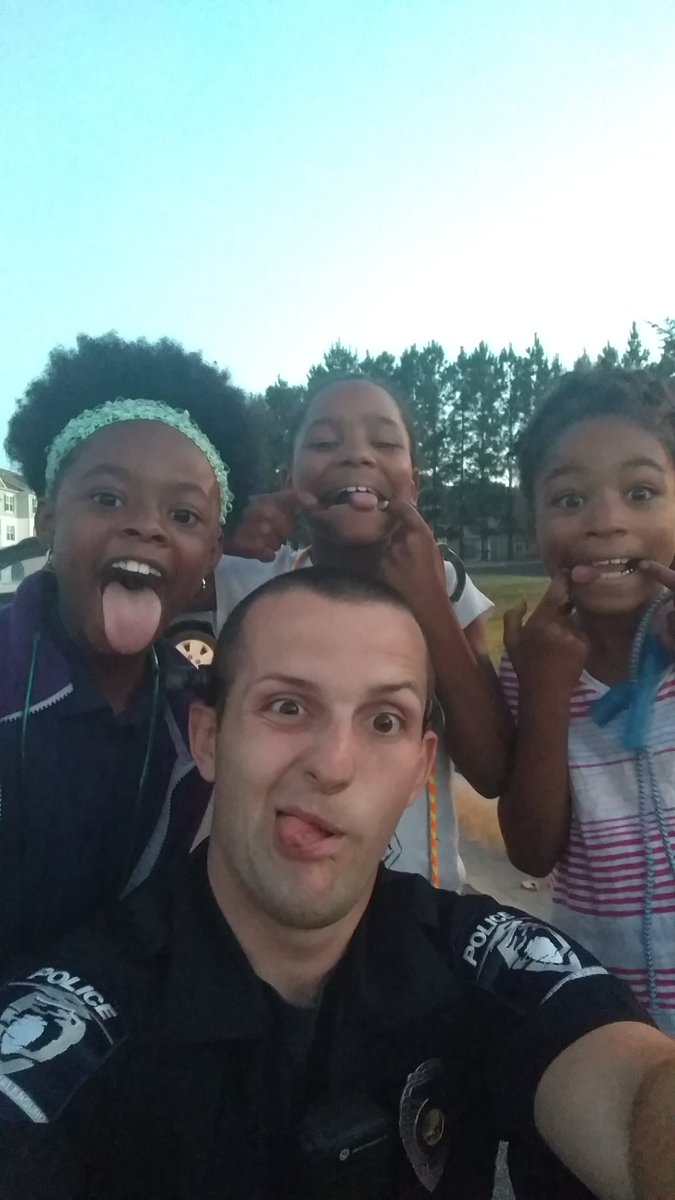 CMPD's tweet photo. These girls struck up a conversation with Officer Furr in their neighborhood. They checked out his police equipment and posed for selfies. https://t.co/lEO4GWj4I3