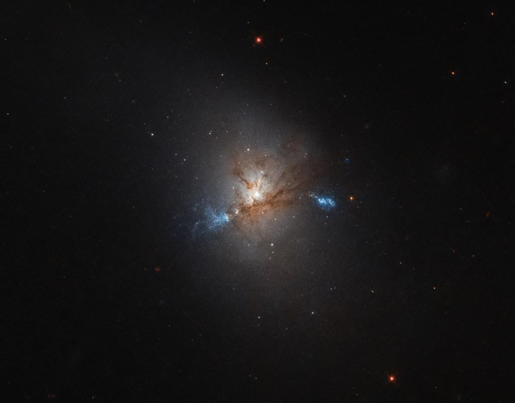 NASA's tweet photo. A hungry giant! Astronomers think this galaxy is swallowing up two much smaller dwarf galaxies. Details: https://t.co/7FakFOqSwf @NASAHubble https://t.co/OW04bo1AGw