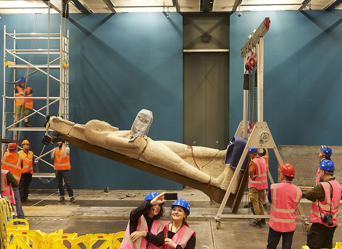 Worthy of a selfie! The British Museum's Sunken Cities exhibition curators capture the moment as a giant statue of Hapy is raised in place.