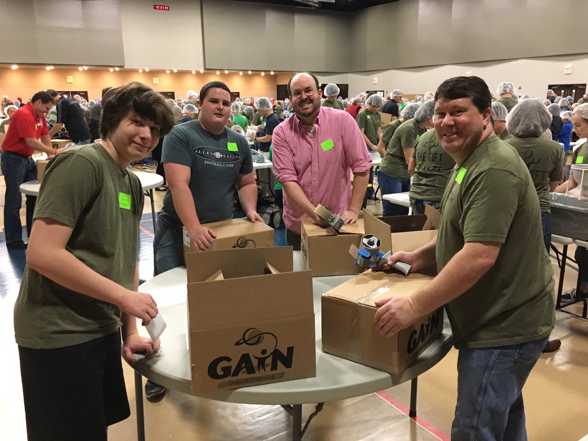 cottonwoodfam's tweet photo. It's the annual missions day called #TheGift2016. Josue - D.R. Pastor - and John pray and address all the meal packers in the gym. https://t.co/0KiXiBsb83