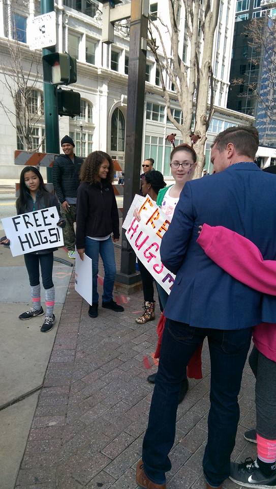 GCSchoolsNC's tweet photo. Students from Southeast High were downtown this Saturday during the Greensboro Holiday Parade spreading community cheer, one hug at a time. https://t.co/WryU5SD9uf