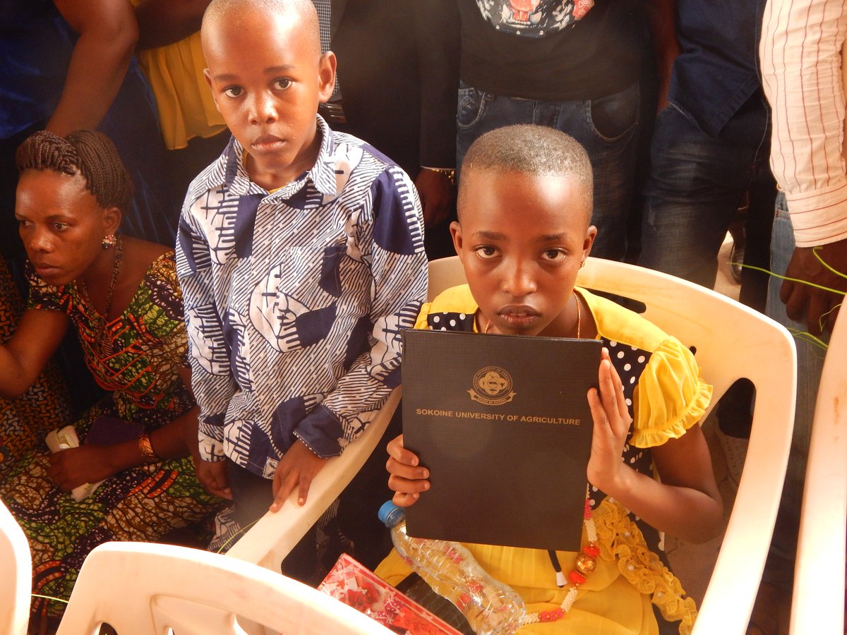 HabariLeo's tweet photo. Mtoto apokea Shahada ya Uzamivu (PhD) ya Chuo Kikuu cha Kilomo Sokoine  kwaniaba ya Mama yake aliyefariki miezi michache kabla ya mahafali. https://t.co/1RMjP8x0oV