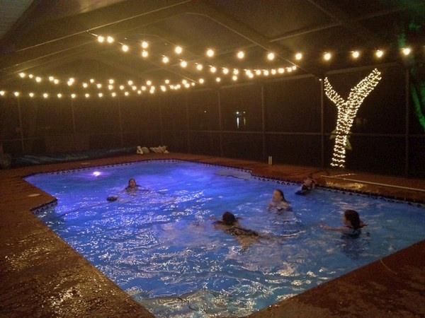 ScreenSolution_'s tweet image. A canopy of string lights over a screened pool deck.