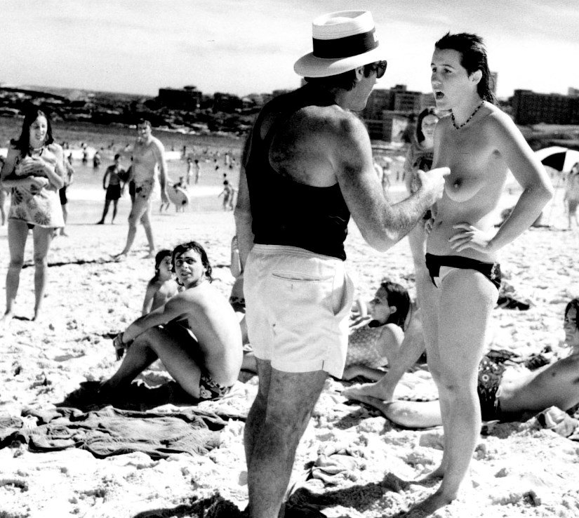 illegal topless swimmer = told by beach inspector to leave the beach = bondi beach = 1975 = Sydney = Australia = photo = mervyn Fitzhenry