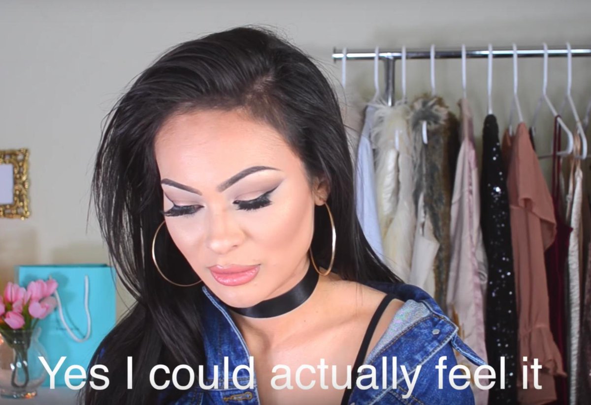 Close-up of beauty vlogger Christine Di Amore, looking down. In the background several outfits hang on a clothes rail. Subtitle reads: Yes I could actually feel it.