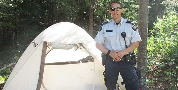 Un policier en uniforme debout près d'une tente.